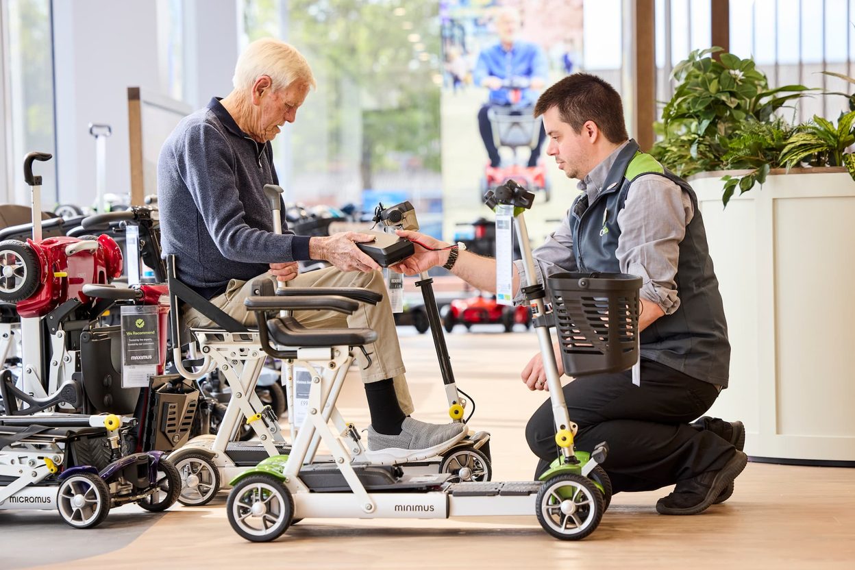 Colleague showing a folding mobility scooter to a customer in the Stockton showroom